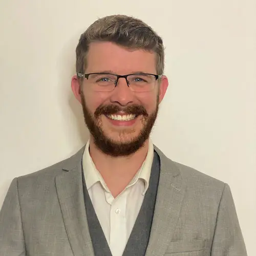 A man in a suit and tie smiling for the camera.