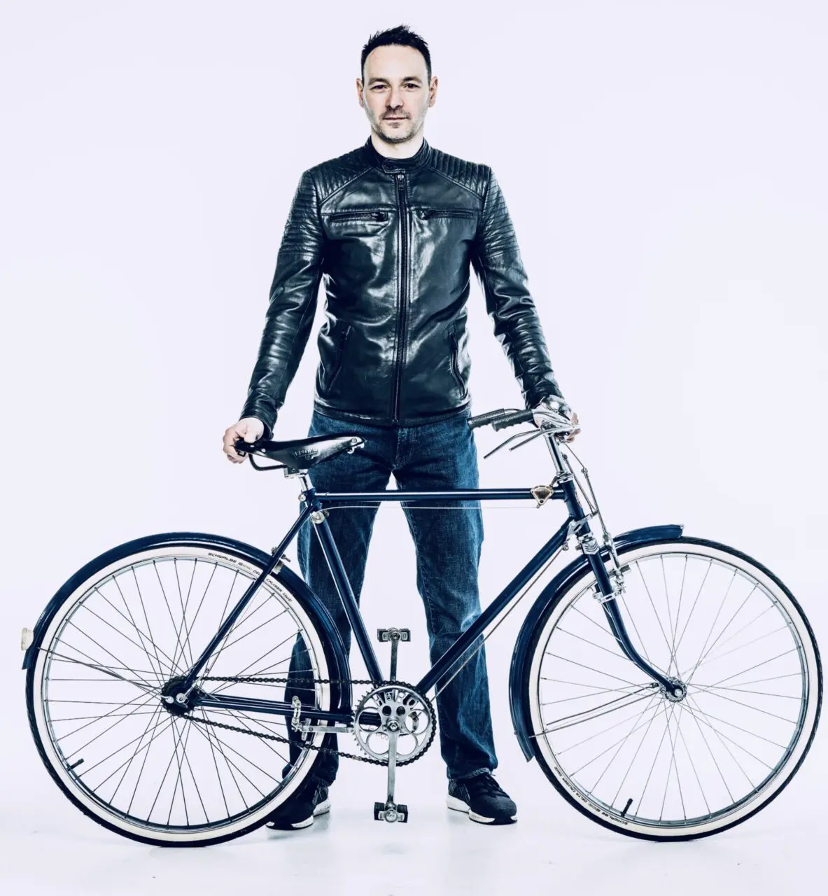 A man in black jacket holding a bike.