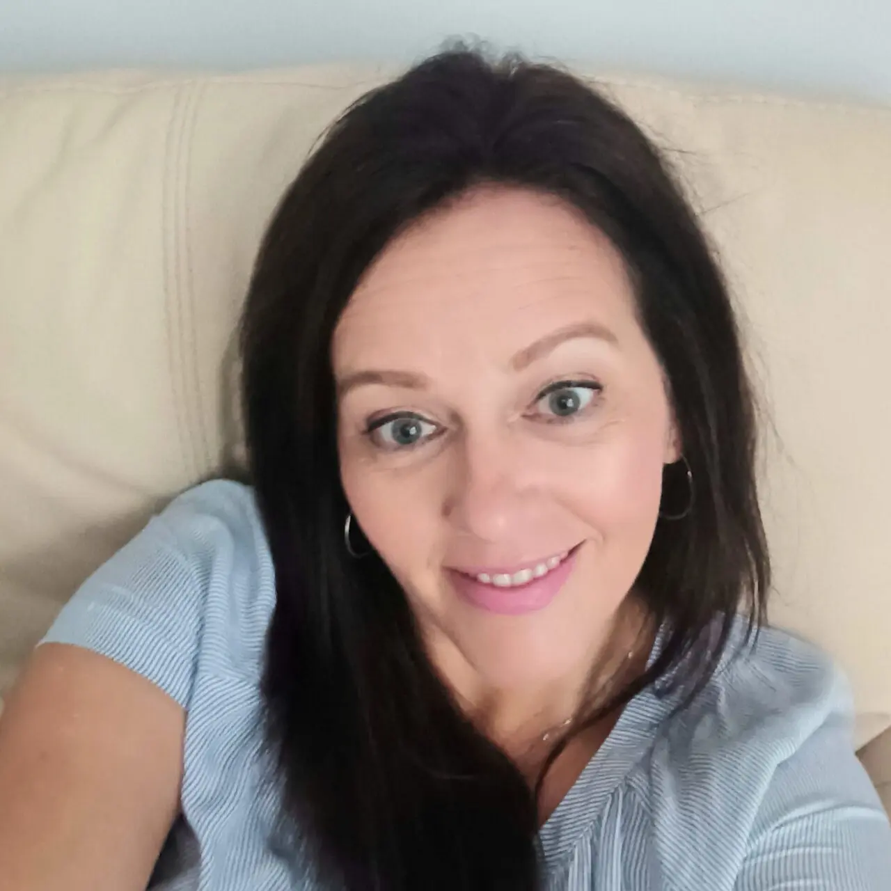 A woman sitting on top of a couch smiling for the camera.